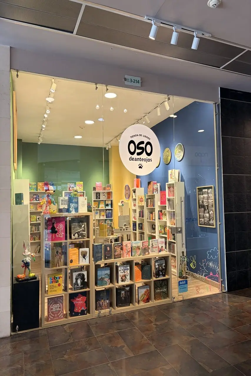 Storefront of a bookstore with colorful shelves of books and a circular OSO deanteojos sign in the window