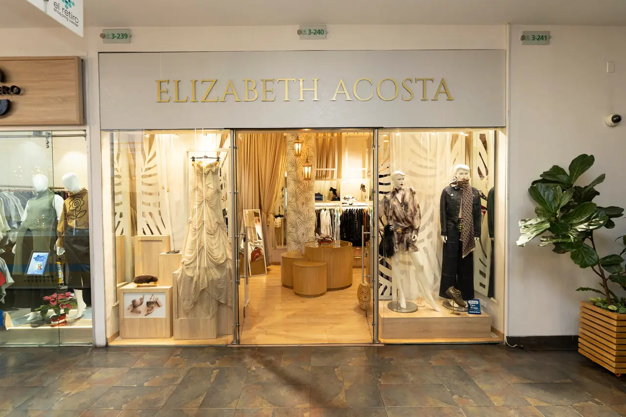 Elizabeth Acosta fashion boutique storefront; glass doors reveal mannequins in cream and black outfits inside a warmly lit shop.