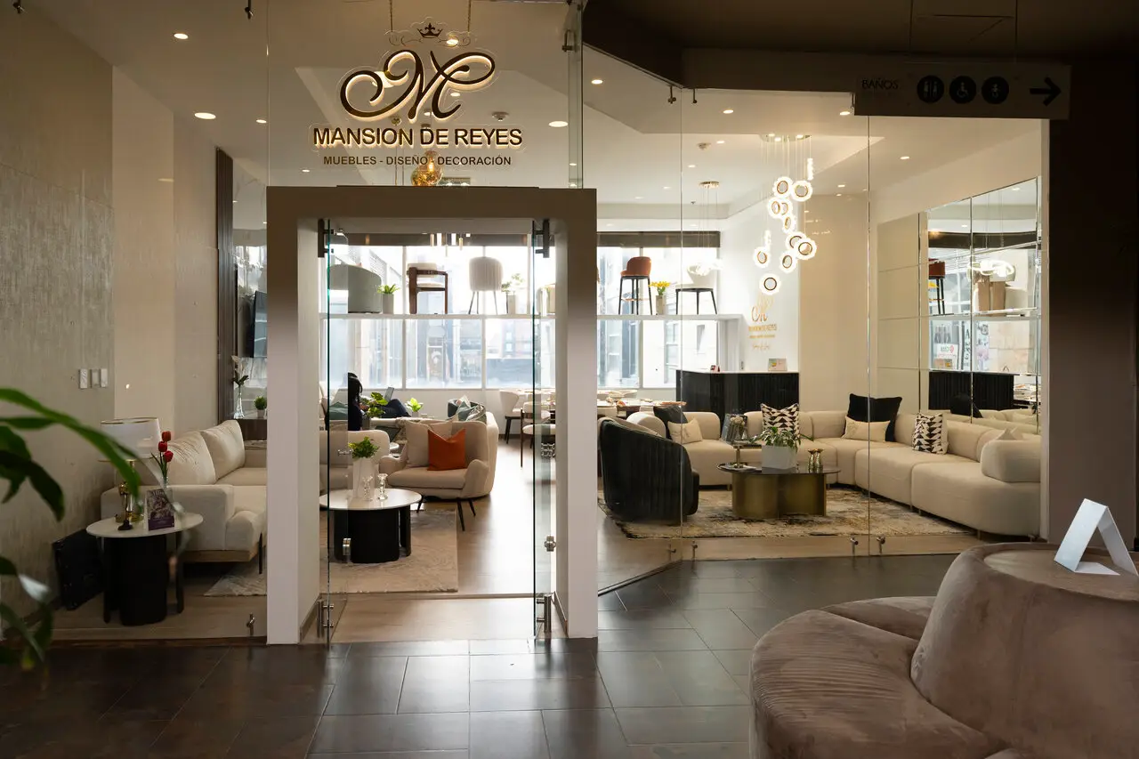 Showroom of Mansion de Reyes furniture store with beige sofas, chairs, and glass walls.
